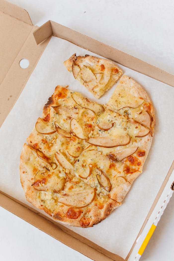 Mastering the First Impression: Your intriguing post title goes here Close-up shot of a gourmet pear and cheese pizza in a cardboard box. Perfect for food lovers.